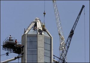 Finishing touches are placed on the 403-foot, glass-enclosed pylon that houses the lighting system. The lights, which will change for holidays, will shift slowly to avoid distracting motorists.