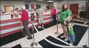 Diana Cicerella waits with her son Sam at AP Federal Credit Union, which originated to serve workers at AP Parts Co.