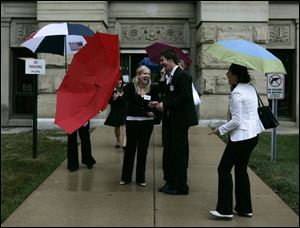 Hungarian law students, from left, Agnes Keszi, Szabolcs Szendr , and Vera Jegesy share a laugh when Agnes  umbrella malfunctions in front of the Lucas County Courthouse.
