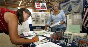 Holly Melick of Tiffin signs a petition in support of saving the Seneca County Courthouse as Nancy Cook looks on.