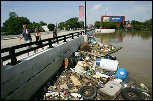 Findlay residents stroll across the Main Street bridge as debris from the recent Blanchard River flooding begins to accumulate along the river s shore.