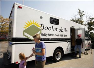 Heidi Rupp and her daughter, Megan, 3, of Findlay leave the bookmobile that serves in place of the main Findlay-Hancock County Library, which has been closed since the flooding.