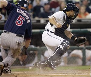 The Twins' Michael Cuddyer scores as Tigers catcher Ivan Rodriguez can't come up with Timo Perez's throw from left field.