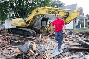 Richard Hendrickson inspects his handiwork after tearing down a nuisance property on West Central Avenue last week. Known as 'the King' by his co-workers, Mr. Hendrickson says it's sad to see buildings be-come neglected, but he takes
pride in taking them down safely and is happy when cleared sites are developed anew for the neighborhood.