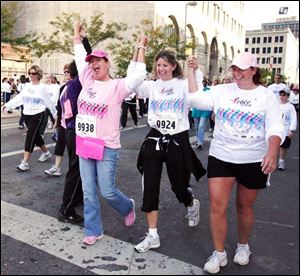 Molly Henry, from left, Karen Baumgartner, and Chere Foster cross the finish line at the race yesterday that began at Fifth Third Field, moved through downtown and North Toledo, and ended at the ball park. 