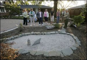 Norma Stark, right, shows a group of visitors the zen garden.
