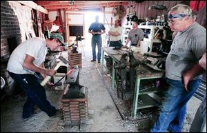 Derrick Bliss, 16, left, hammers a steel rod into shape during the Northwest Ohio Blacksmiths open forge meeting at his shop in Ida, Mich. Derrick is the youngest of the 80-member group.