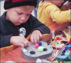 Austin Rogers, 5, of Sylvania makes a mask, one of several child-friendly crafts that were available.