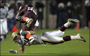 Boston College s Jamie Silva dives to tackle Virginia Tech tailback Brandon Ore with one arm.
