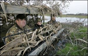 James Donnell Konkel, left, Heather Braun and Kent Felbinger keep watch over Rusk Marsh on Sandusky Bay hoping to get a shot off during a day of duck hunting recently.