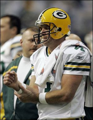 Packers quarterback Brett Favre holds his right arm, injured Thursday night in a game against the Dallas Cowboys.