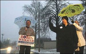 Bruce Weirauch, left, Robin Weirauch, and campaign worker Antonia Pogacar stand outside of Eagle Point Elementary School in Rossford this morning.