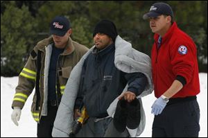 Frederick Dominguez, center, is helped to an ambulance after being rescued with his three children by a California Highway Patrol helicopter.