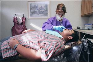 Patient James Maynard, 12, travels 60 miles from Paulding, Ohio, to Bowling Green to see his dentist, Jack Whittaker. Here, hygienist Tammy Rogowski cleans his teeth.