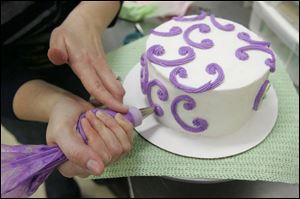 Icing is piped onto a cake.