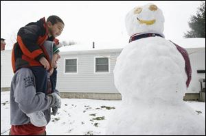 There was enough snow for a snowman on Maumee's Shelly Avenue where Taylor Monus, 17, carries Blake Olvear, 6.