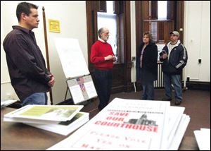 Seneca County Commissioner Ben Nutter, left, along with Jim Stultz, center, speaks to Janelle and Steve Reino about Gov. Ted Strickland s interest in the courthouse. Mr. Nutter favored demolition early on, saying it would be irresponsible to start restoration
without a plan to pay for it. Now he says he wants to
consider aid for renovation. Commissioner Dave
Sauber has sided with Mr. Nutter. Commissioner Mike Bridinger has worked for renovation.
