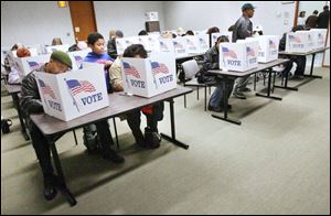 Brandon Jackson, 9, center, keeps an eye on his parents, Brady Jackson and Felicitas Jackson of Holland, who cast early votes. 