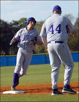 Bluffton University s Cody McPherson is congratulated by
coach James Grandey after hitting a home run during yesterday s opening game against Eastern Mennonite University.
