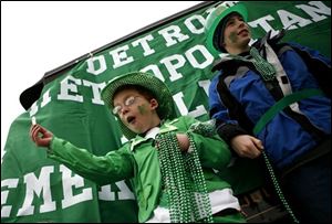 Jacob Ball, 9, of Saline, Mich.,holds gold-colored coins and beads with Grant Geiger, 11, of Saline,while riding on one of the parade floats in the St. Patrick's Day parade in Detroit on Sunday.