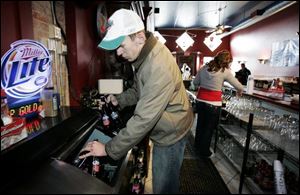 Ryan Proudlock stocks a cooler at the establishment near the Mud Hens stadium in downtown Toledo. 