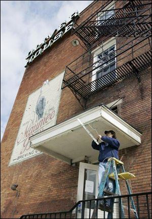 Jeff Kerekes, a maintenance man at the Oliver House on Broadway, installs new lighting over an entrance to the building. Over the past several months, floor restoration, painting, and plastering have been done on the near-downtown building that houses several restaurants. 