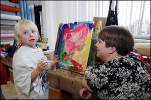 At right, Alyssa Haynes, 5, of Rossford receives instruction from studio arts teacher Ami Saar regarding her work titled 'Spiderman.' The budding artists are entering their works in the fourth annual Children's Art Show the week of April 11-17 in Owens Math/Science Galleria. The youngsters are sons and daughters of Owens staff and students. The college will open the exhibit tomorrow, and the reception and exhibit are open to the public. The art exhibit is the culmination of a year of training at the child-care center.