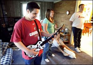 Jacob Tanner, left, of Maumee and his sister Marissa play a video game while their family watches. Jacob, 16, was 18 months old when he first showed signs of autism.  
