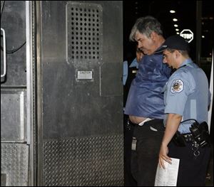 Donald Wells of Metamora, Mich., identified by hospital spokesman Sean Howard as the driver of a truck that was involved in a rush hour accident. is taken into police custody on Friday in Chicago. The 64-year-old truck driver has been cited for negligent driving after ramming his semitrailer into a Chicago Transit Authority train station. (ASSOCIATED PRESS)
<br>
<img src=http://www.toledoblade.com/graphics/icons/video.gif> <b><font color=red>AP VIDEO</b></font color=red>: <a href=