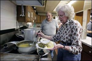 Terry and Kathryn Rathbun, serving lunch at the community center, say the all-volunteer soup kitchen is struggling as donations dwindle. The center serves hot meals three days a week.