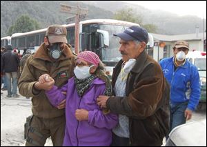 Residents wear protective masks as they evacuate the village of Futaleufu near the Chaiten volcano in southern Chile on Tuesday. The Chaiten volcano spewed incandescent material and blasted ash into the sky on Tuesday, prompting a total evacuation of the provincial capital and other settlements. (ASSOCIATED PRESS)
<br>
<img src=http://www.toledoblade.com/graphics/icons/video.gif> <b><font color=red>VIDEO</b></font color=red>: <a href=