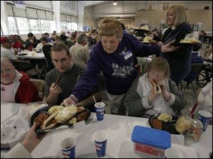 Thelma Littler hands a plate to a guest as Brandon Slaymaker and Annette Arzinger, both from Fremont, make way for the 87-year-old woman who's in charge of the picnic lunch and fun day for mentally handicapped children and adults of Sandusky and Seneca counties.