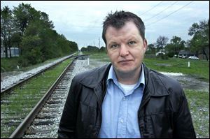 Jason Lang lois, a Lucas County sheriff s deputy, stands along the tracks where railroad Detective Frank Smith was shot by robbers in 1916. The site is near Bowsher High School. Detective Smith got skipped over, Mr. Langlois said. 
