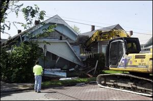 City worker Tim Schnatterly hoses debris to keep the dust down as co-worker Richard Hendrickson maneuvers the bulldozer to demolish the house on Greenwood Avenue. (BLADE PHOTOS/JETTA FRASER)
<br>
<img src=http://www.toledoblade.com/graphics/icons/forum.gif> <b><font color=red>TALK BACK</b></font color=red>: Join <a href=