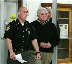 The Rev. Frank Murd, center, is escorted into Lucas County Common Pleas Court by a sheriff's deputy and followed by his attorney, Tom Matuszak. Father Murd pleaded not guilty to sexual imposition in connection with an alleged incident with a man, 27, in a hot tub at the YMCA/JCC in Sylvania.