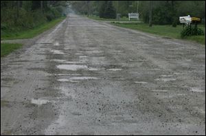 Potholes pepper a three-mile stretch of Rauch Road. Officials are trying to come up with money to make repairs.