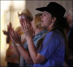 Mandi Dewulf sings and claps along with the music at St. Andrew s.