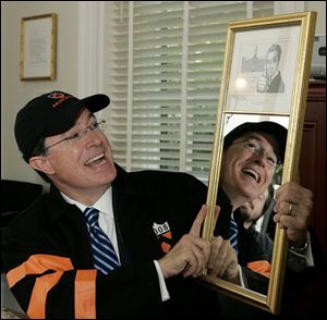 Stephen Colbert wears a Princeton cap and jacket as he holds up an award mounted on a mirror given to him after addressing 2,611 Princeton graduates-to-be assembled at Class Day, which is held each year the day before commencement on Monday, in Princeton. Colbert, the host of his own Comedy Central show, Emmy winner, faux presidential candidate, and best-selling author, on Monday, added to that esteemed collection an award from Princeton University: 