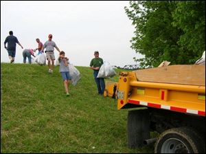 The Blade's Steve Pollick, right, helps rural Fremonter Robert Haas and daughter Cheyann carry bags to a waiting truck.