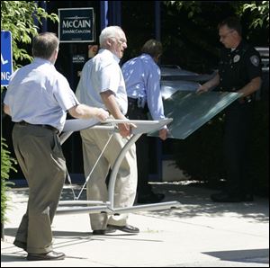 Outgoing Chairman Bob Reichert and others carry items into party headquarters. Former Executive Director Joanne Wack removed items, but Maumee police ordered them returned.