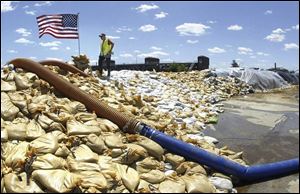Standing atop a mountain of sandbags, Davenport Street Department employee Don Korch looks over the flooding Mississippi River in downtown Davenport, Iowa on Tuesday.