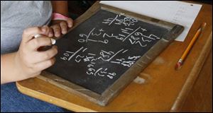 Ben Andrus does a math exercise on a chalk slate.