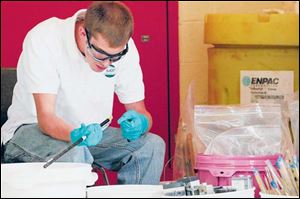 Teddy Rader of Rader Environmental Services tries to identify mercury in items collected by Bowling Green State University's mercury reclamation program. 