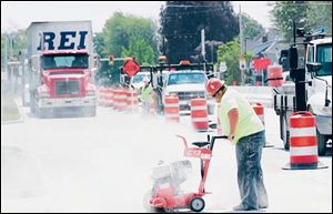 Tod Boose of Smith Paving Inc. of Norwalk, Ohio, cuts new concrete on U.S. 20 on Woodville's west side. On Monday, traffic on U.S. 20 will be shifted over to the 
newly built north half of the roadway within the 
village limits
so work may proceed on the existing roadway.
