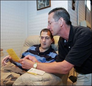 Joe Loy shows Jamie Mercurio a program from the benefit game Jamie played in at Cory-Rawson High School in 1993.