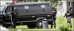 Armed Ottawa County deputies watch the home where a former soldier barricaded herself.