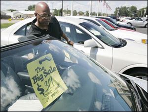 Salesman Zack Clark prepares a sign in a car for sale at Grogan
Towne Chrysler-Dodge in Toledo.