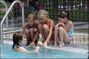 Ann Peltier, 10, cools off in the water while talking to, from left, Molly Musgrave, 7, her sister Abby Musgrave, 9, and Bailee Markowiak, 8, at Pickford Park Aquatic Facility in Toledo. Many public pools reached capacity early in yesterday's heat. 