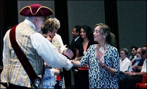 Michael Lieber, Sylvania s town crier, congratulates
Fatma El Sweafi Amer, a native of Egypt, on becoming a U.S. citizen after naturalization ceremonies held at the Fifth Third Center at One SeaGate in downtown Toledo. Ms. Amer was one of 28 people yesterday who took the oath of citizenship administered by U.S. District Court Judge Jack Zouhary.
