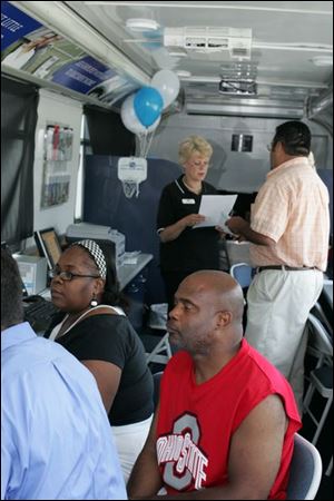 BIZ mobile23p  Bertha and Darryl (cq) Faison, of Toledo, seated, speaking with Justin Hickerson, left and back to camera, a mortgage loan originator. Standing at rear are Linda Zawacki, a personal banker, and Greg Flores, a mortgage loan originator. All but the Faisons are with Fifth Third Bank. Fifth Third Bank's Homeownership 